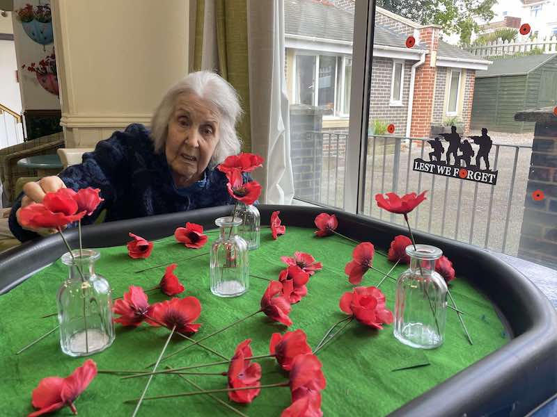 residents putting poppies into glass bottles