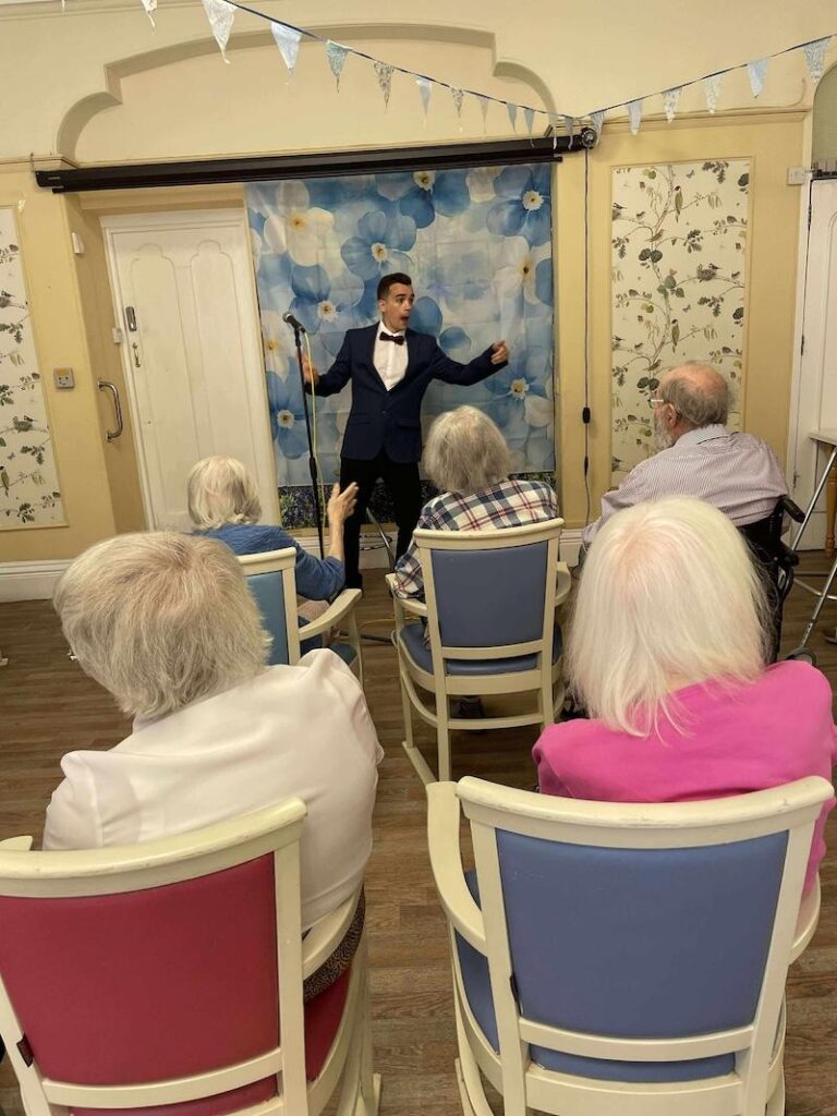 entertainer stood at the front of the lounge performing to residents
