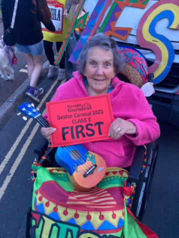 Resident in a wheelchair holding the first place certificate at seaton carnival
