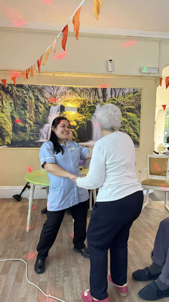 Resident dancing with carer in lounge